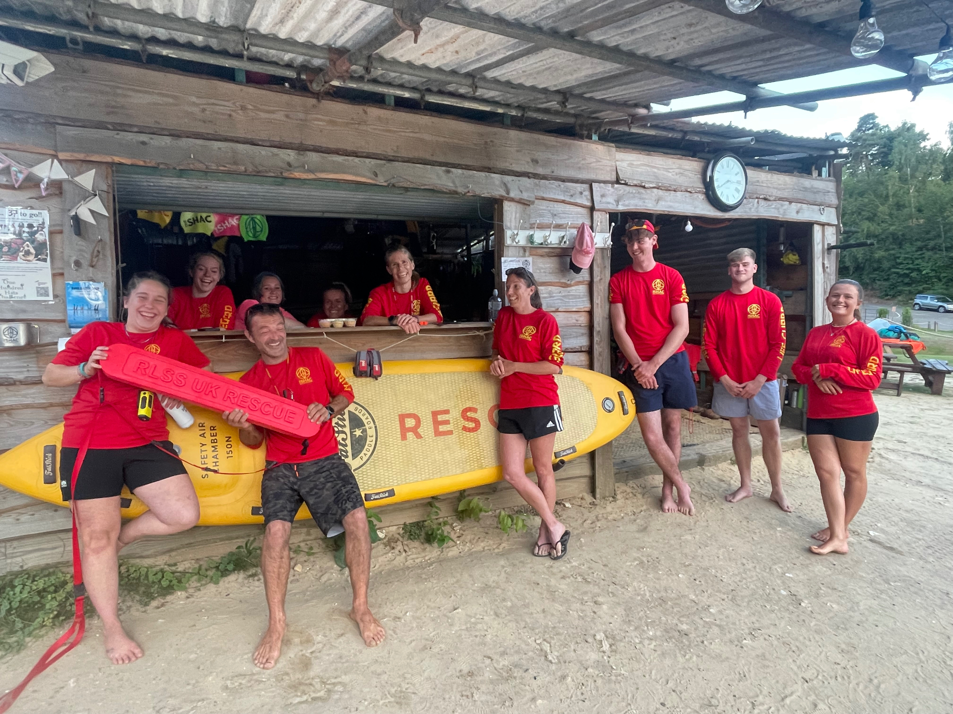 The SHAC lifeguard team gathered around a rescue board outside the lifeguard hut at Buckland Park Lake
